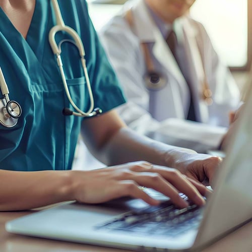 A nurse entering data and working on a laptop